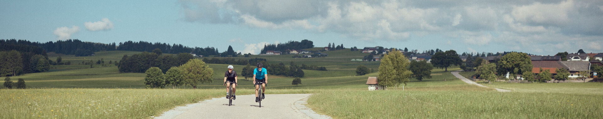 Zwei Rennradfahrer fahren auf einem Güterweg im Mühlviertel.