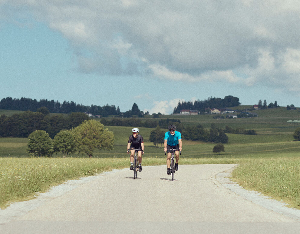 Zwei Rennradfahrer fahren auf einem Güterweg im Mühlviertel.