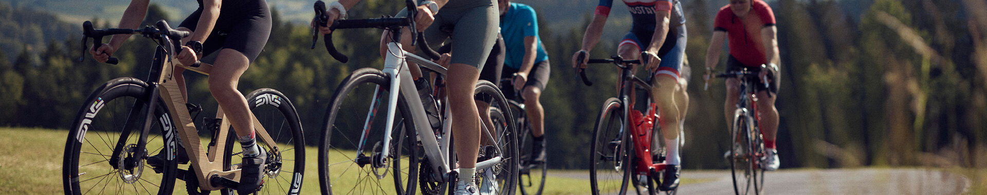 Rennradfahrer fahren einen Feldweg entlang mit Panoramablick.